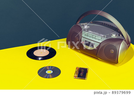 Colorful image of vintage radio player on bright yellow tablecloth isolated over dark green background 89379699