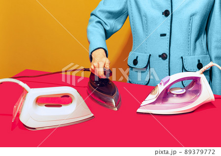 Colorful bright image of female ironing pink tablecloth with retro iron isolated over yellow background 89379772