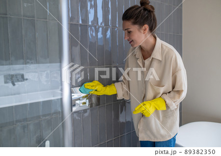 Yung housewife looking busy while cleaning in the bathroom Yung housewife looking busy while cleaning in the bathroom 89382350