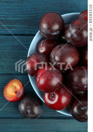 Blue bowl with plums on a blue wooden table 89383310