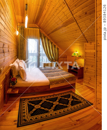 Mansard bedroom with natural wood trim in country house with double bed 89384126