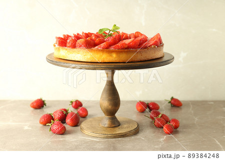 Wooden stand with strawberry tart on gray textured table 89384248