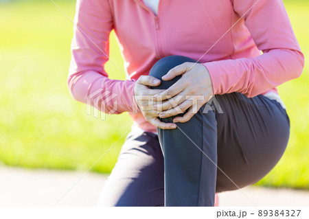 運動中に痛めたヒザを押さえるミドル女性 運動中に痛めたヒザを押さえるミドル女性 89384327