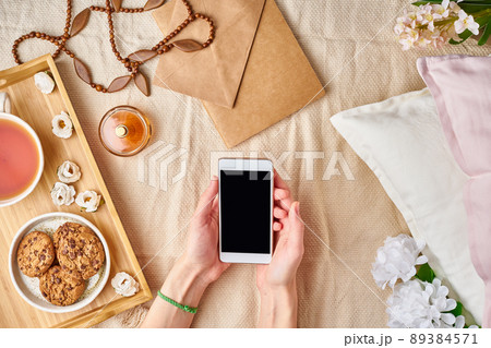 Flatlay women's hands holding a smartphone. Cozy home rest, vacation, weekend. Flatlay women's hands holding a smartphone. Cozy home rest, vacation, weekend. 89384571