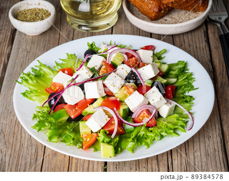 Greek salad on white plate on old rustic wooden table, side view 89384578