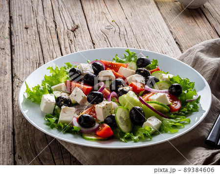 Greek salad on white plate on old rustic wooden table, side view, copy space Greek salad on white plate on old rustic wooden table, side view, copy space 89384606