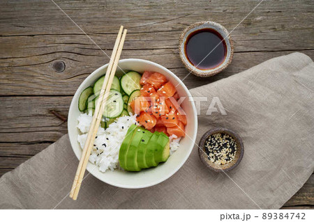 Salmon poke bowl with fresh fish, rice, cucumber, avocado with black and white sesame Salmon poke bowl with fresh fish, rice, cucumber, avocado with black and white sesame 89384742
