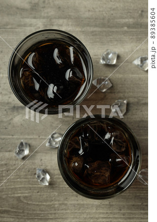 Glass of cola and ice on gray textured table 89385604