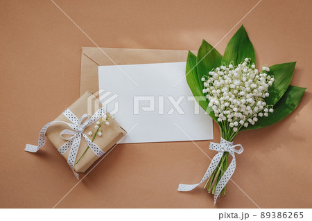 Lily of the valley and empty notepad with text copy space on beige background Lily of the valley and empty notepad with text copy space on beige background 89386265