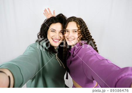 Portrait of happy mom and teen daughter spend time together. Teenage girl hugging her mother and having fun together 89386476