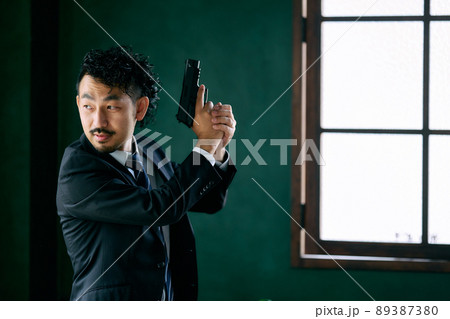 拳銃を持つ髭の男性 89387380