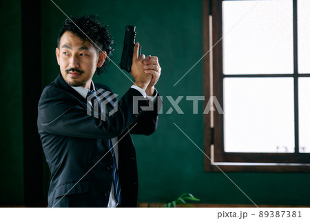 拳銃を持つ髭の男性 89387381