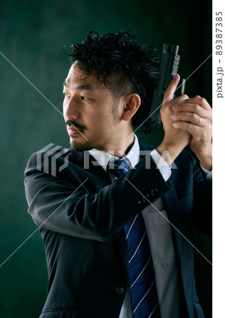 拳銃を持つ髭の男性 89387385