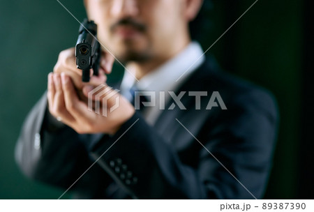 拳銃を持つ髭の男性 89387390