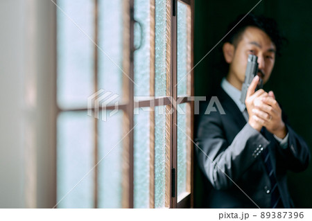 拳銃を持つ髭の男性 89387396
