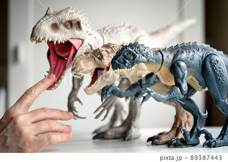 Hand touches dinosaur toys standing on the table. 89387443