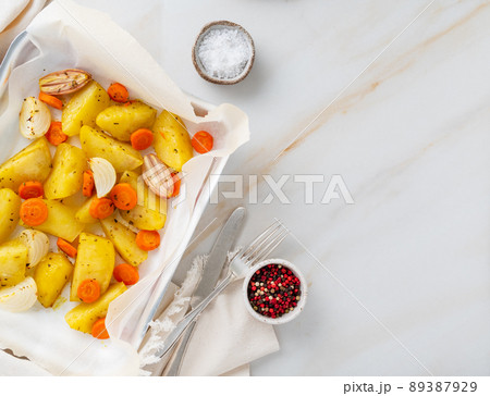 Colorful roasted vegetables on tray with parchment. Potatoes, carrots and onions. Colorful roasted vegetables on tray with parchment. Potatoes, carrots and onions. 89387929