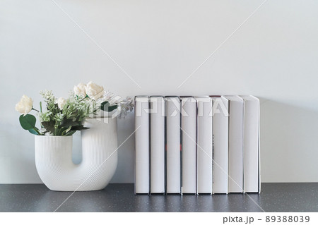 Beautiful curved vase with flowers close-up. Collection of books. Flowers in interior design. Cozy house. High quality photo Beautiful curved vase with flowers close-up. Collection of books. Flowers in interior design. Cozy house. High quality photo 89388039