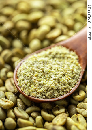 Ground green coffee in a scoop and unroasted coffee beans. Ground green coffee in a scoop and unroasted coffee beans. 89388387