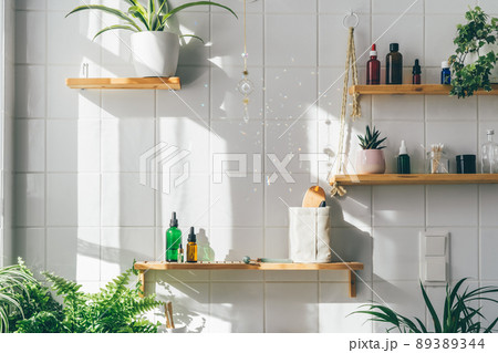 Biophilic desing in modern white bathroom with many green plants. Urban jungle. Natural materials, bamboo, wooden shalves. Shadows from sun light. Wellness and well-being 89389344