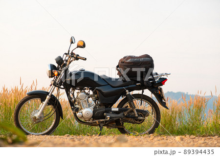 Black retro motorcycle with backpack parked outdoors. Black retro motorcycle with backpack parked outdoors. 89394435