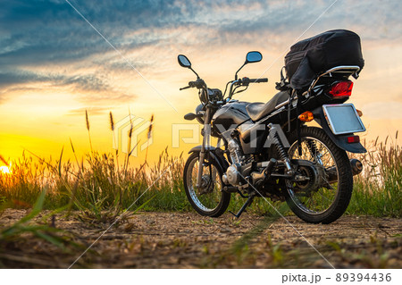Black retro motorcycle with backpack parked outdoors. Black retro motorcycle with backpack parked outdoors. 89394436