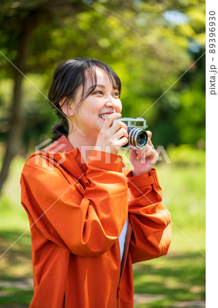 屋外でレトロなフィルムカメラで趣味の写真を撮る若い女性 屋外でレトロなフィルムカメラで趣味の写真を撮る若い女性 89396930
