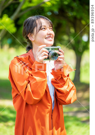屋外でレトロなフィルムカメラで趣味の写真を撮る若い女性 屋外でレトロなフィルムカメラで趣味の写真を撮る若い女性 89396934