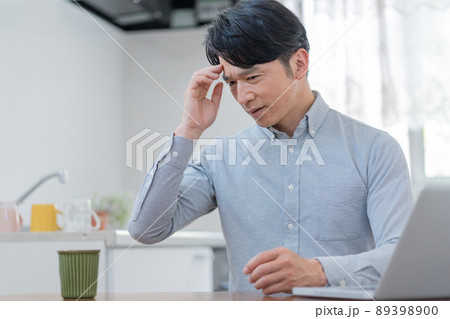 リビングに座って頭を触る困った顔の中年男性 頭痛 リビングに座って頭を触る困った顔の中年男性 頭痛 89398900