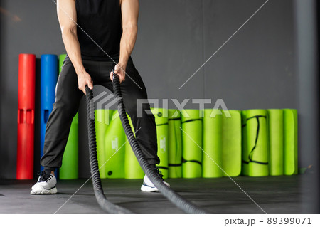 Strong Asian sportive man standing in a ready position for doing a battle rope exercise in a indoor gym with copyspace. Powerful young sportsman training a body building concept, muscle building. Strong Asian sportive man standing in a ready position for doing a battle rope exercise in a indoor gym with copyspace. Powerful young sportsman training a body building concept, muscle building. 89399071