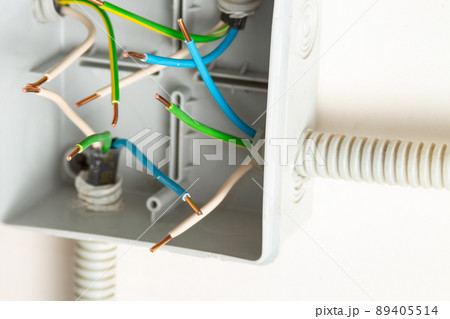 Bare contacts of electrical wires in a junction box on the wall 89405514