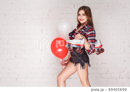 Happiness woman with air balloon and vintage roller skates toothy smiling. Studio shot, isolated on brick wall 89405699