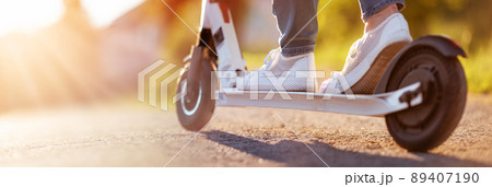 Woman riding on scooter on asphalt road in summer Woman riding on scooter on asphalt road in summer 89407190