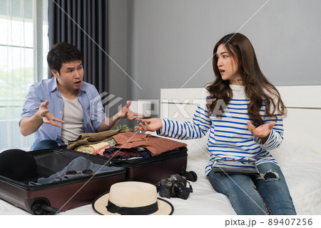 stressed couple having problem with packing clothes into a suitcase on bed at home, holiday travel concept stressed couple having problem with packing clothes into a suitcase on bed at home, holiday travel concept 89407256