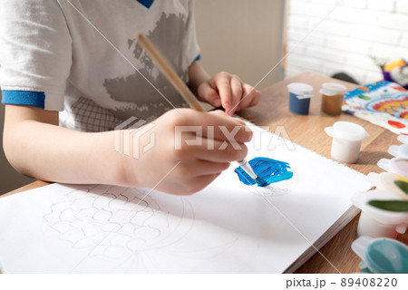 Kid drawing with blue gouache paint in album close up Kid drawing with blue gouache paint in album close up 89408220