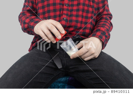 Man takes semen analysis. Spermogram. Concept. Male with his pants unbuttoned symbolizes preparation for analysis of seed for infertility, sperm motility. Suitability test for artificial insemination 89410311
