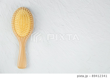 A wooden hair massager comb lies on a white textured background. High quality photo 89412341