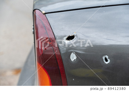 Close-up of the rear of the shelled car. Sedan with through holes from shrapnel. The war in Ukraine 2022. Russian aggression. The shelling of civilians. War crimes concept 89412380