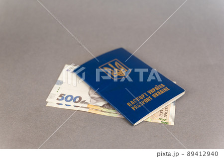A blue covered passport and cash against a gray background. Ukrainian ID card and hryvnias. 89412940