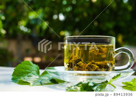 Glass cup of mulberry leaf tea on white table background. 89413936