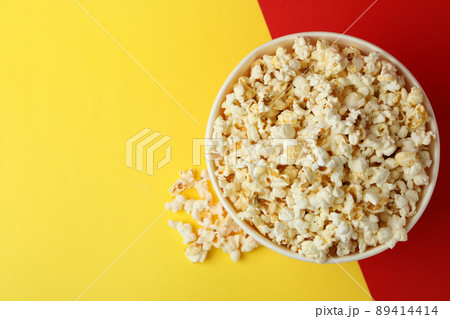 Striped paper cup with popcorn on two tone background Striped paper cup with popcorn on two tone background 89414414