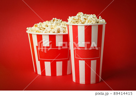 Paper cups with popcorn on red background 89414415