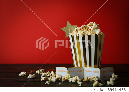 Paper box with popcorn, and tickets against red background Paper box with popcorn, and tickets against red background 89414428