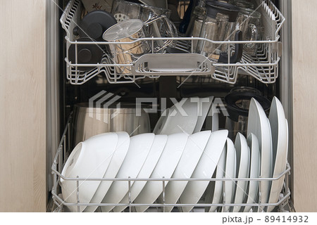 Full loaded Dishwasher machine. Integrated Dishwasher with white plates front vew. 89414932