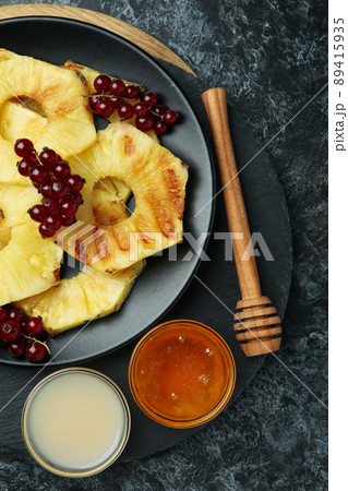 Concept of tasty food with grilled pineapple on black smokey background. 89415935