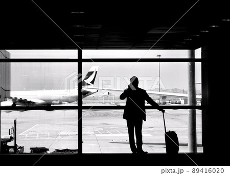 飛行機を眺めながら電話する男性 89416020
