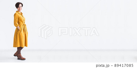 clothing, designer, people concept - attractive woman in a yellow dress posing on white room banner and place for advertising clothing, designer, people concept - attractive woman in a yellow dress posing on white room banner and place for advertising 89417085