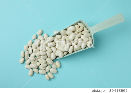 Scoop of white beans on blue background Scoop of white beans on blue background 89418665