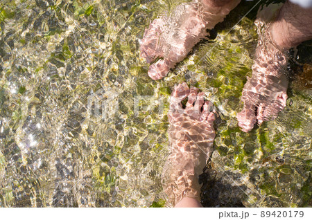 The concept of a couple on vacation, women's feet and men's feet in the water on a rock in the sea. Front view. The concept of a couple on vacation, women's feet and men's feet in the water on a rock in the sea. Front view. 89420179