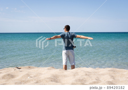 Man stands by the sea and enjoys it. The concept of oneness with nature and relaxation, tourism. Front view. Man stands by the sea and enjoys it. The concept of oneness with nature and relaxation, tourism. Front view. 89420182